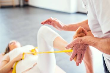 Durchführung einer Übung mit Flexiband zur Behandlung des Beins der Patientin