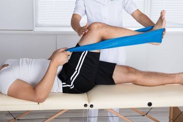 Physiotherapeut hilft Patient bei der Durchführung von Übungen mit Flexiband