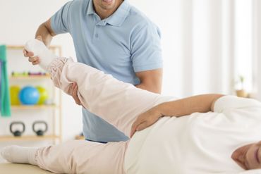 Physiotherapeutin behandelt das Bein eines Patienten