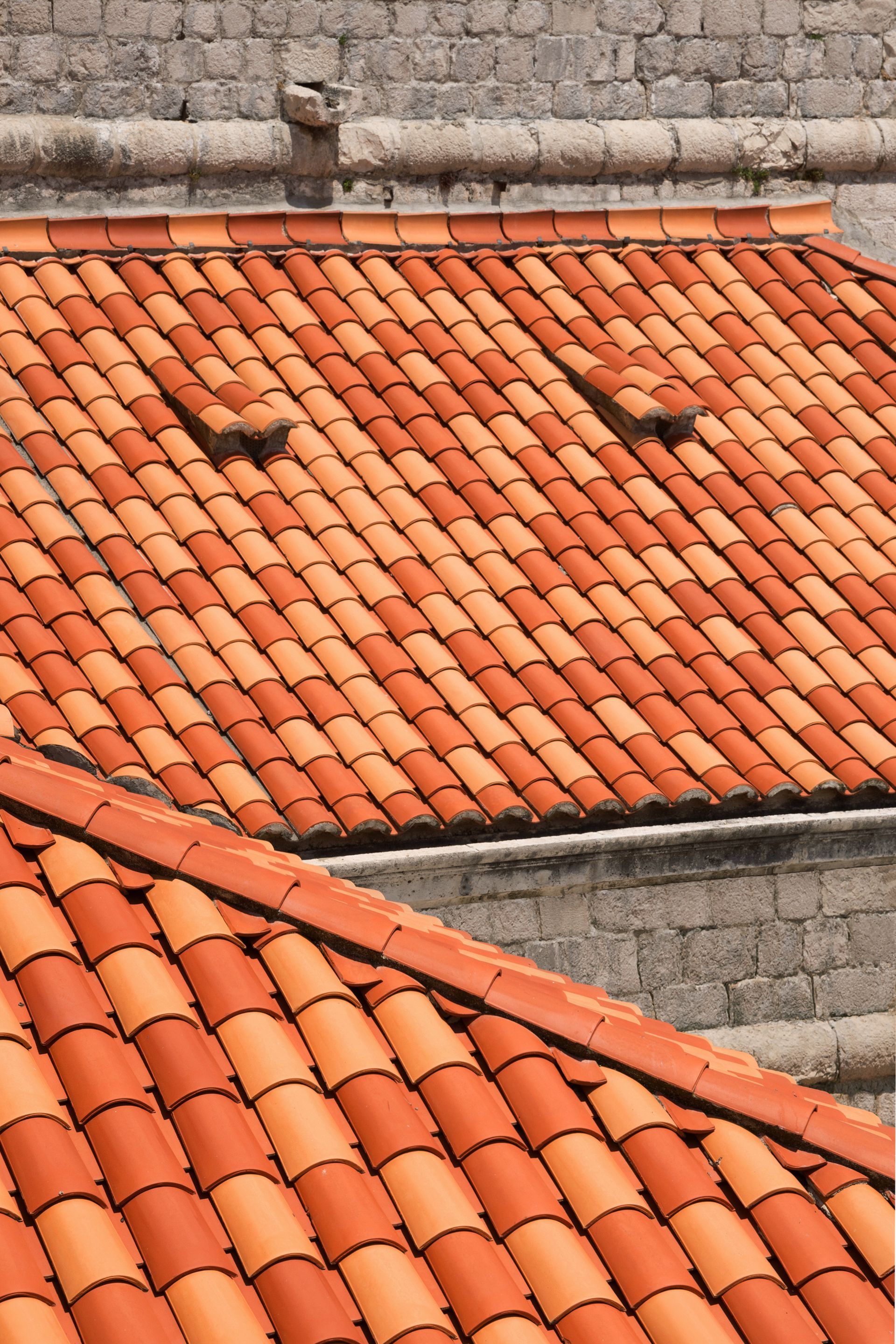 Toits de tuiles rouges contre un mur de pierre.