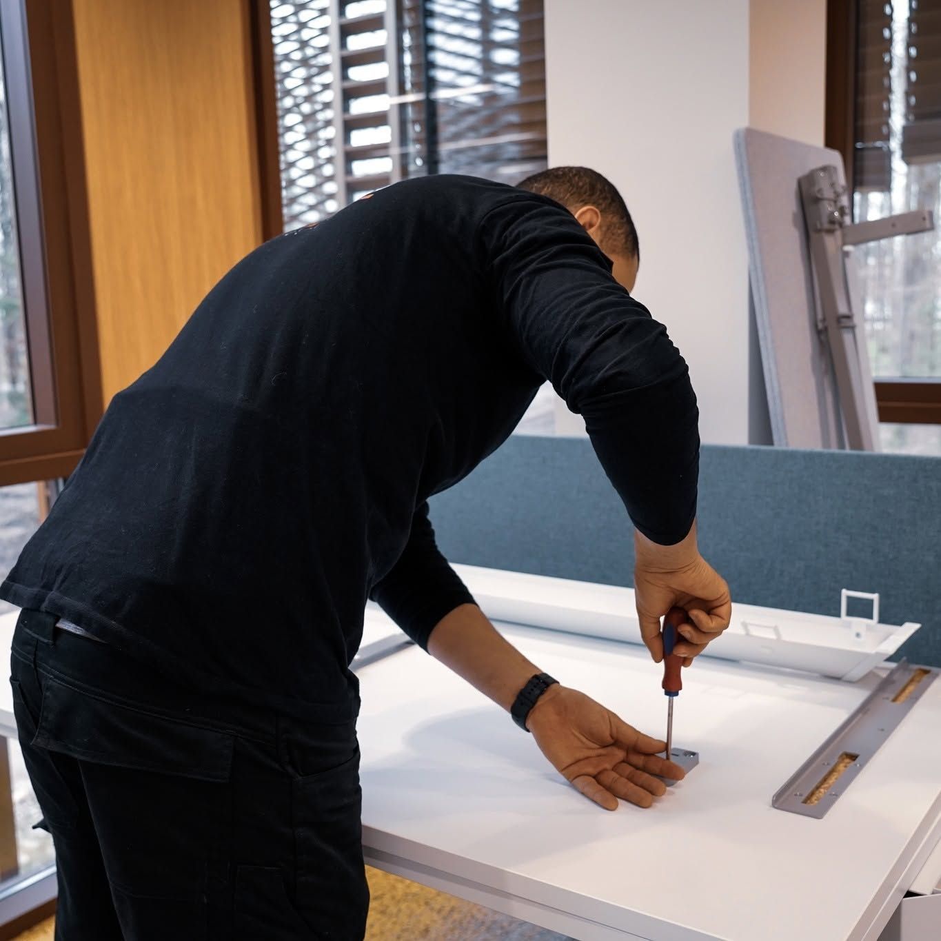 Personne penchée au-dessus d’un tableau blanc, en train de mesurer et de tracer des repères au crayon