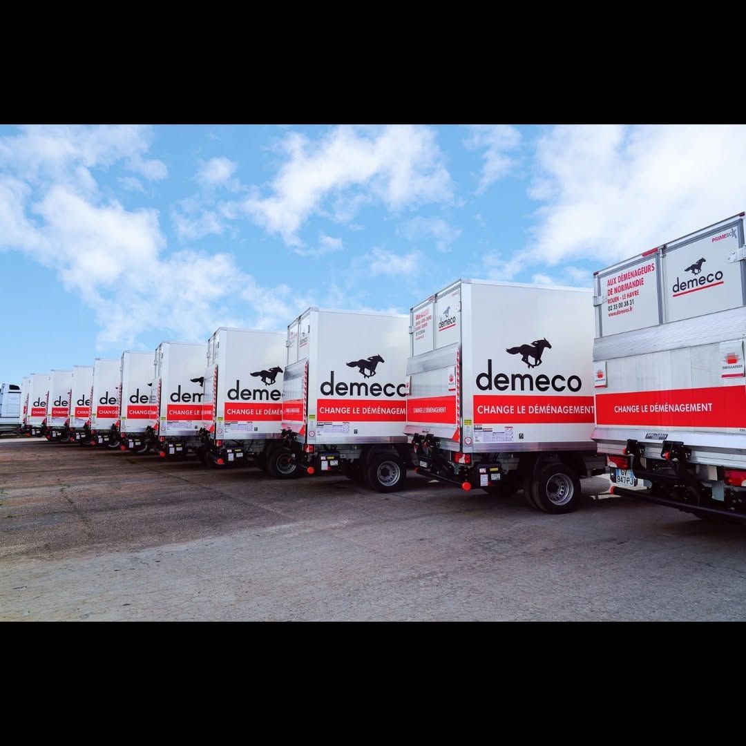 Rangée de camions de livraison blancs Demeco garés à l’extérieur sous un ciel bleu