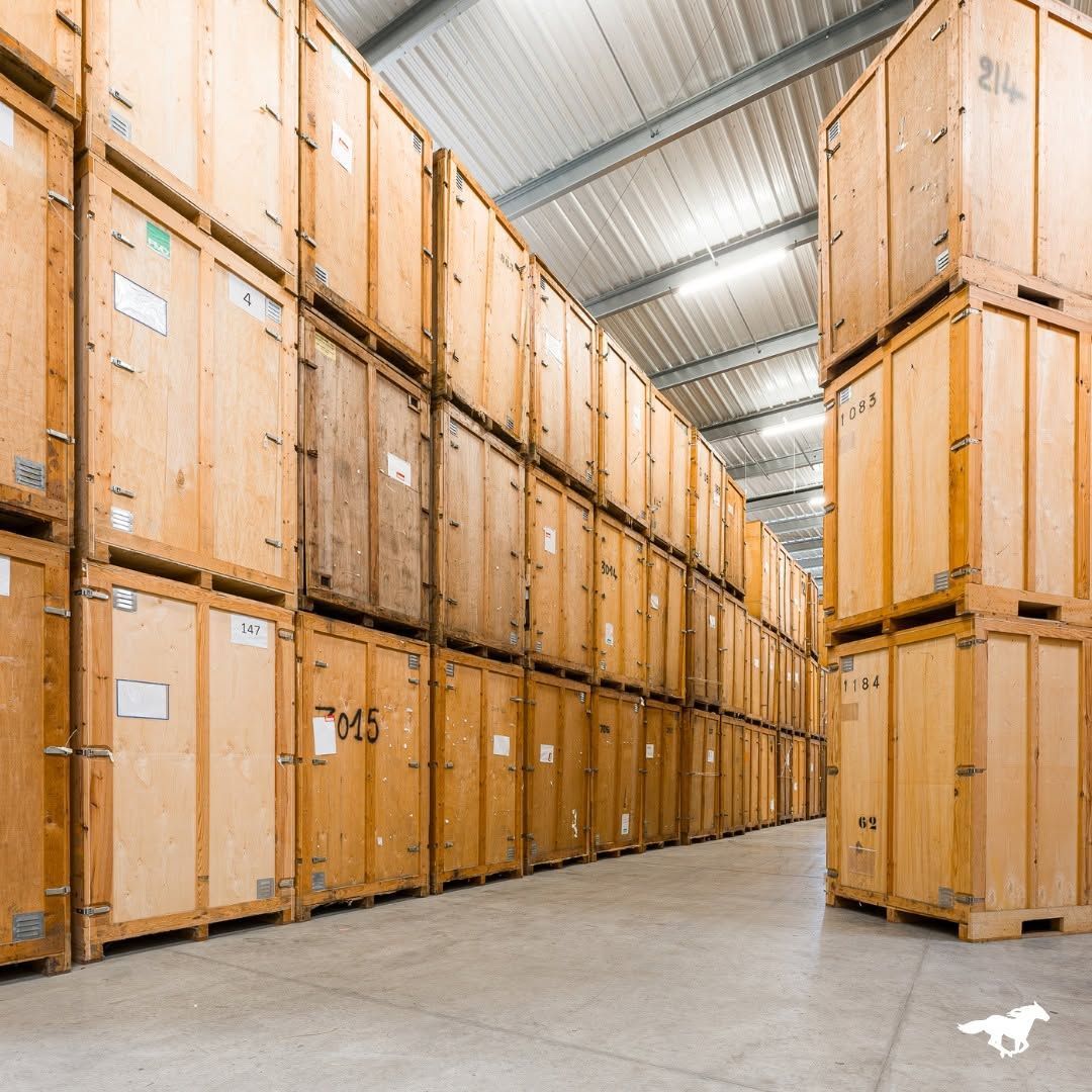 De hautes piles de caisses d’expédition en bois dans une allée d’entrepôt, avec un sol en béton et un toit métallique