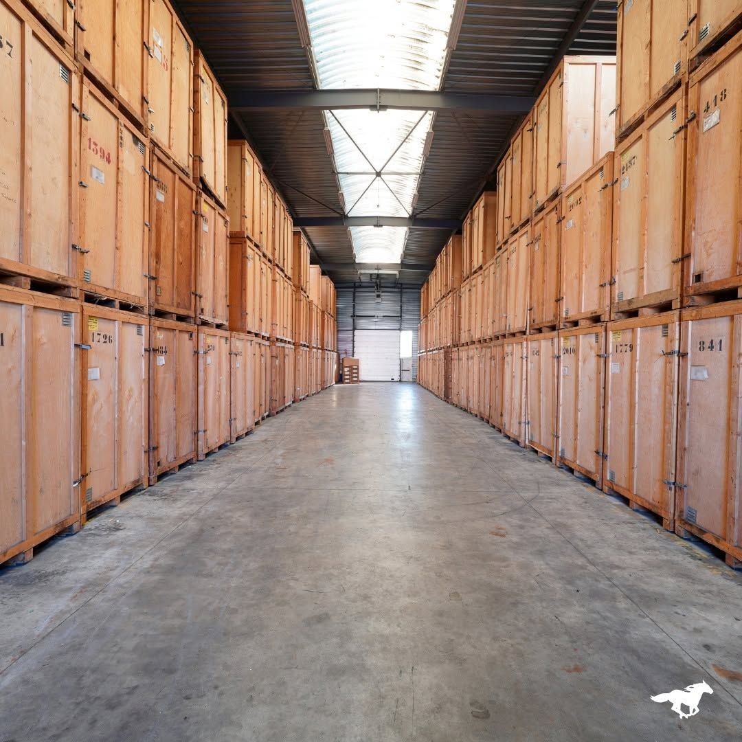 Dans une allée d’entrepôt, des piles de caisses d’expédition en bois bordent les deux côtés sous un plafond élevé.