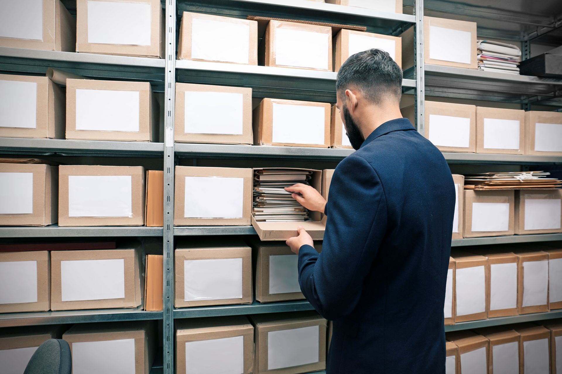 Personne étiquetant des cartons sur des étagères d’entrepôt dans une réserve