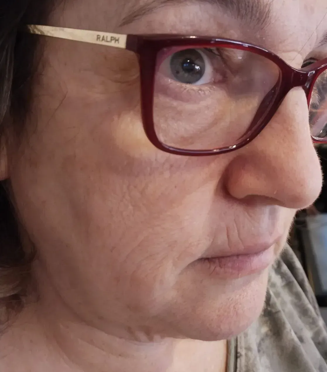 Mujer que lleva gafas de montura roja, mirando ligeramente hacia un lado con una expresión neutra.