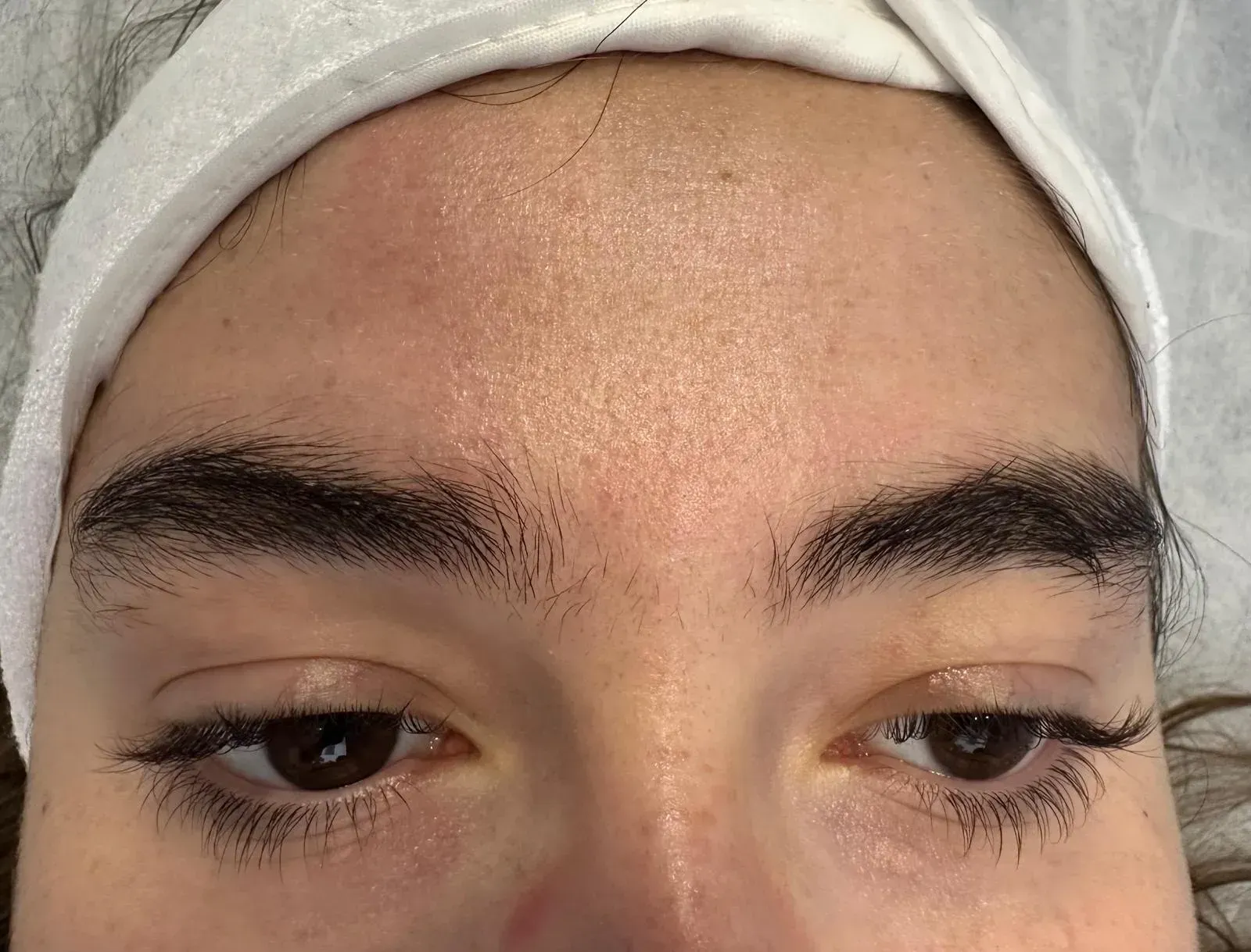 Rostro de una persona con cejas pobladas y ojos oscuros, con una diadema blanca. 