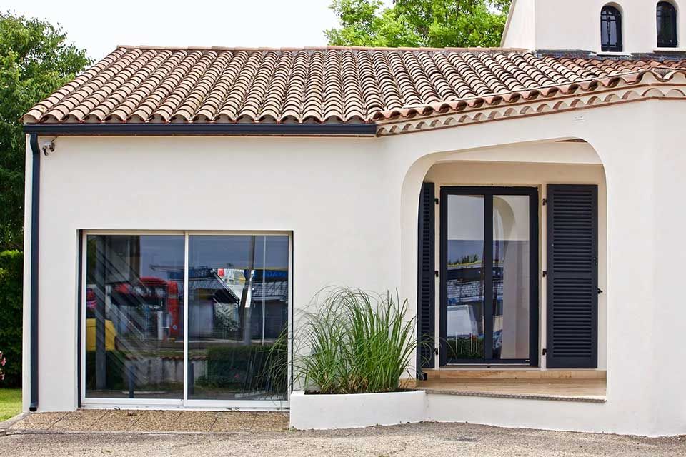 Vue de la façade avec baie vitrée et porte-fenêtre d'une maison témoin Maisons Guitard