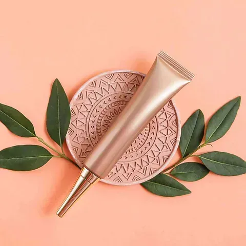 Un tubo de loción reposa sobre un plato con hojas verdes.