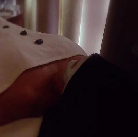 Una persona está acostada en una cama con una toalla sobre la cabeza.