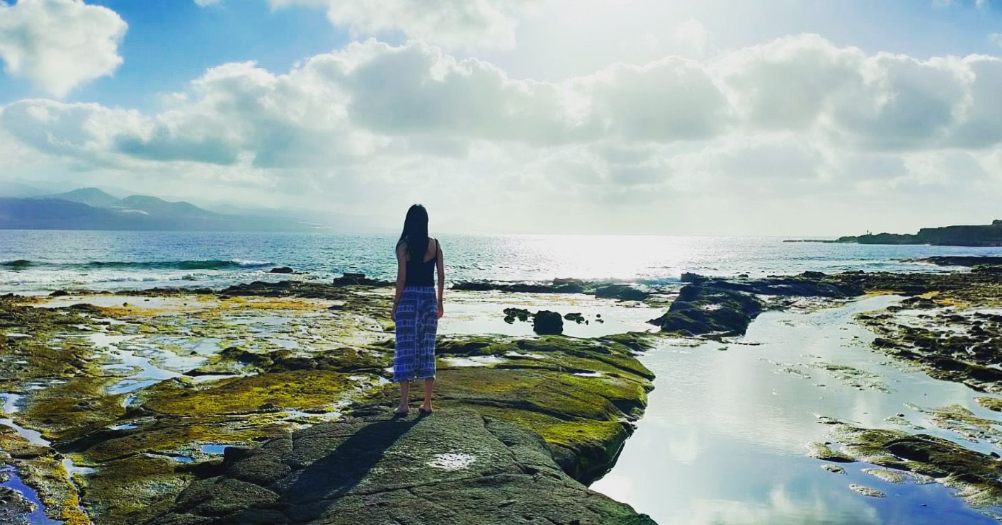 Una mujer está parada en un muelle con vistas al océano.