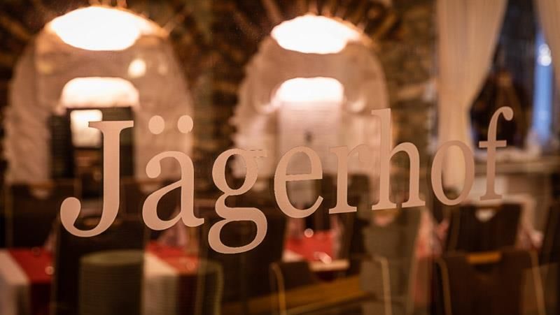 Ein verschwommenes Bild eines Restaurants mit dem Wort „Jägerhof“ auf dem Fenster.