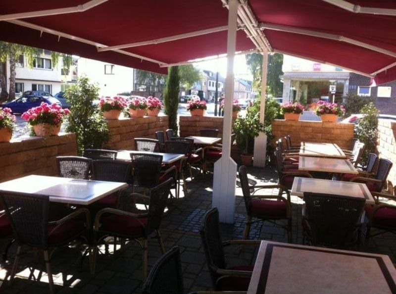 Ein Restaurant mit Tischen und Stühlen unter einem roten Sonnenschirm