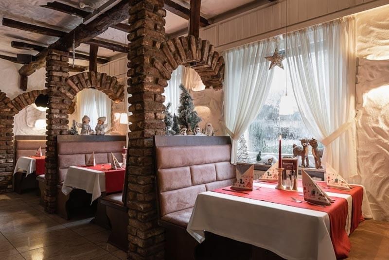 Ein Restaurant mit Tischen und Bänken und einem Weihnachtsbaum im Fenster.