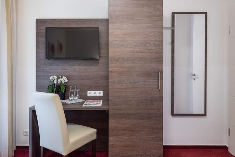 Ein Hotelzimmer mit Schreibtisch, Stuhl, Fernseher und Spiegel.