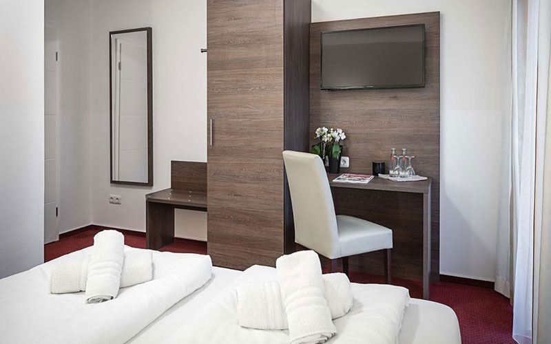 Ein Hotelzimmer mit Bett, Schreibtisch, Stuhl und Fernseher.