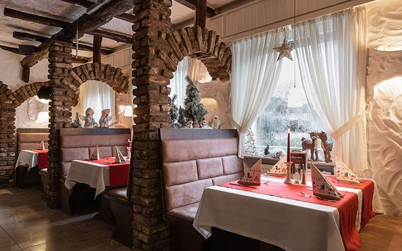 Ein Restaurant mit Tischen und Bänken und einem Weihnachtsbaum im Fenster.