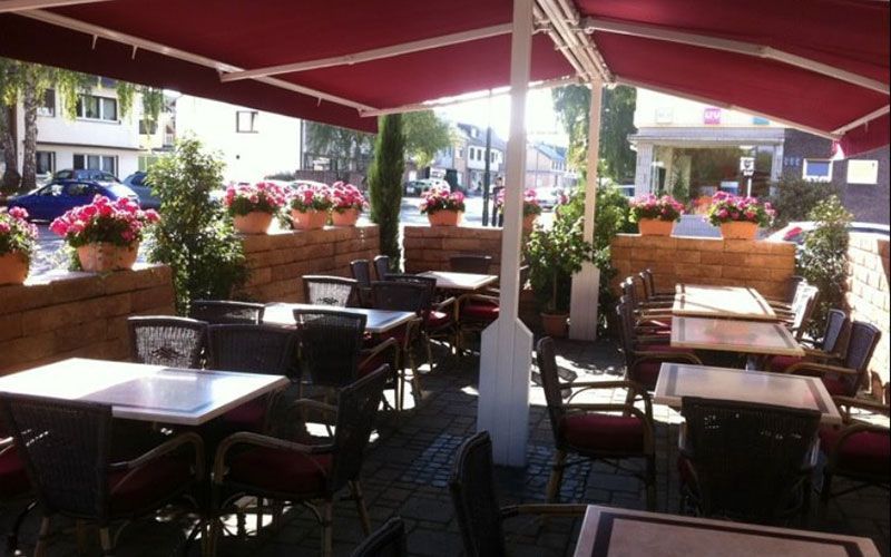 Ein Restaurant mit Tischen und Stühlen unter einem Sonnenschirm