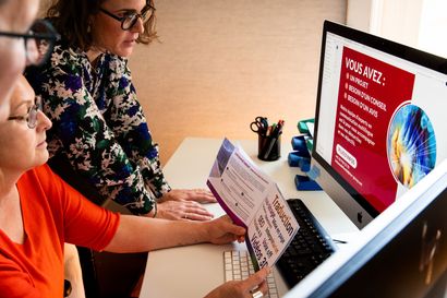Deux personnes travaillent sur un ordinateur et examinent une diapositive rouge affichée à l'écran.