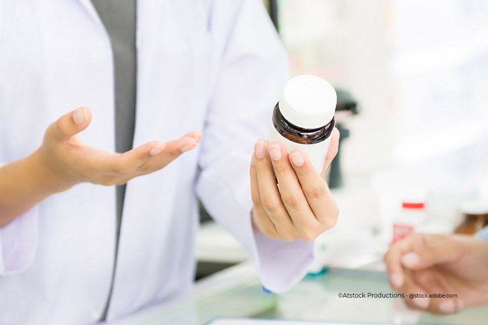 Mitarbeiterin der Ring-Apotheke Maja Schmieade e.K. hält ein Medikament in der Hand und erklärt etwas