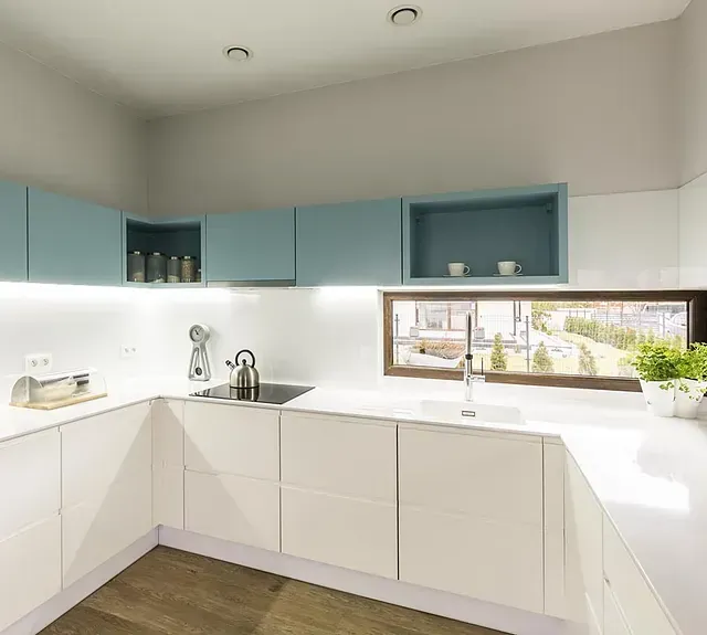 Una cocina con gabinetes blancos, un fregadero y una ventana.