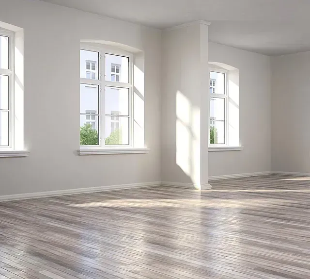Una habitación vacía con suelo de madera y muchas ventanas.