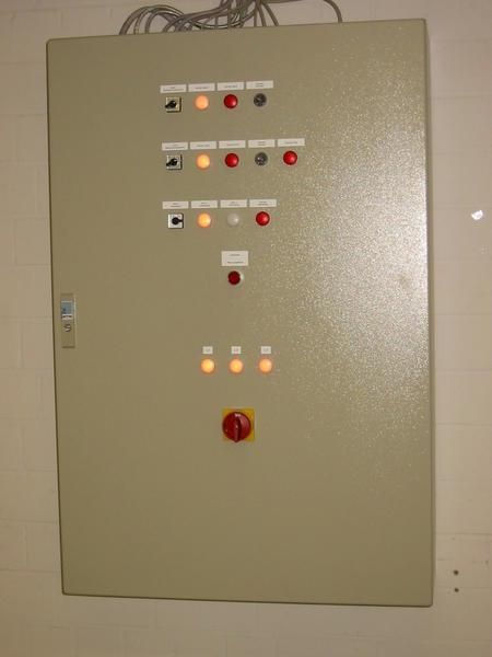 An einer Wand hängt ein großer Schaltkasten mit Knöpfen.