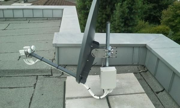 Auf dem Dach eines Gebäudes steht eine Satellitenschüssel.