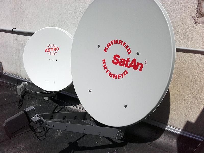 Zwei weiße Satellitenschüsseln mit dem Wort Satan darauf