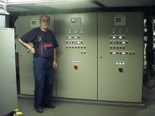 Ein Mann im Overall steht vor einem Bedienfeld