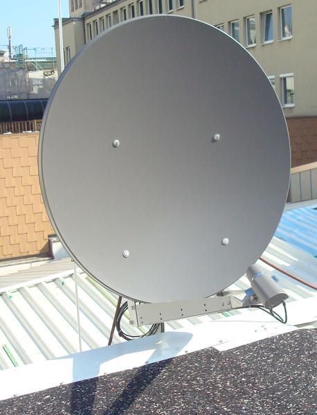 Eine große Satellitenschüssel steht auf einem Dach