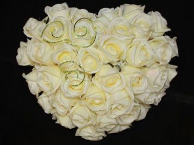 Bouquet de roses blanches en forme de cœur avec des touches dorées sur fond noir.