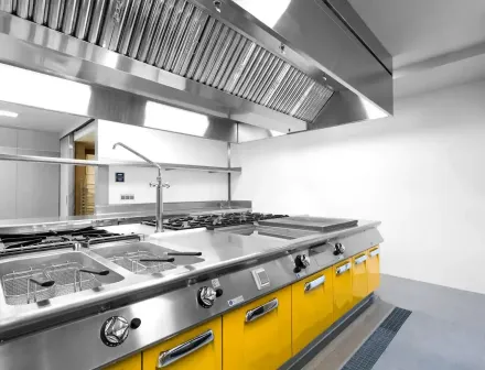 Cocina comercial con gabinetes amarillos y electrodomésticos de acero inoxidable.