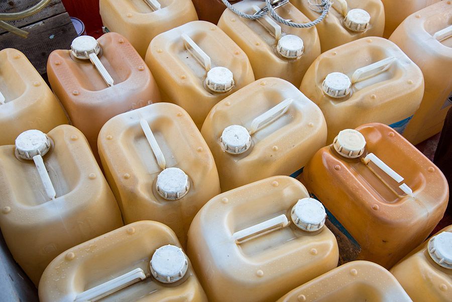 Contenedores de combustible de plástico de color amarillo, dispuestos muy juntos, con tapas blancas.