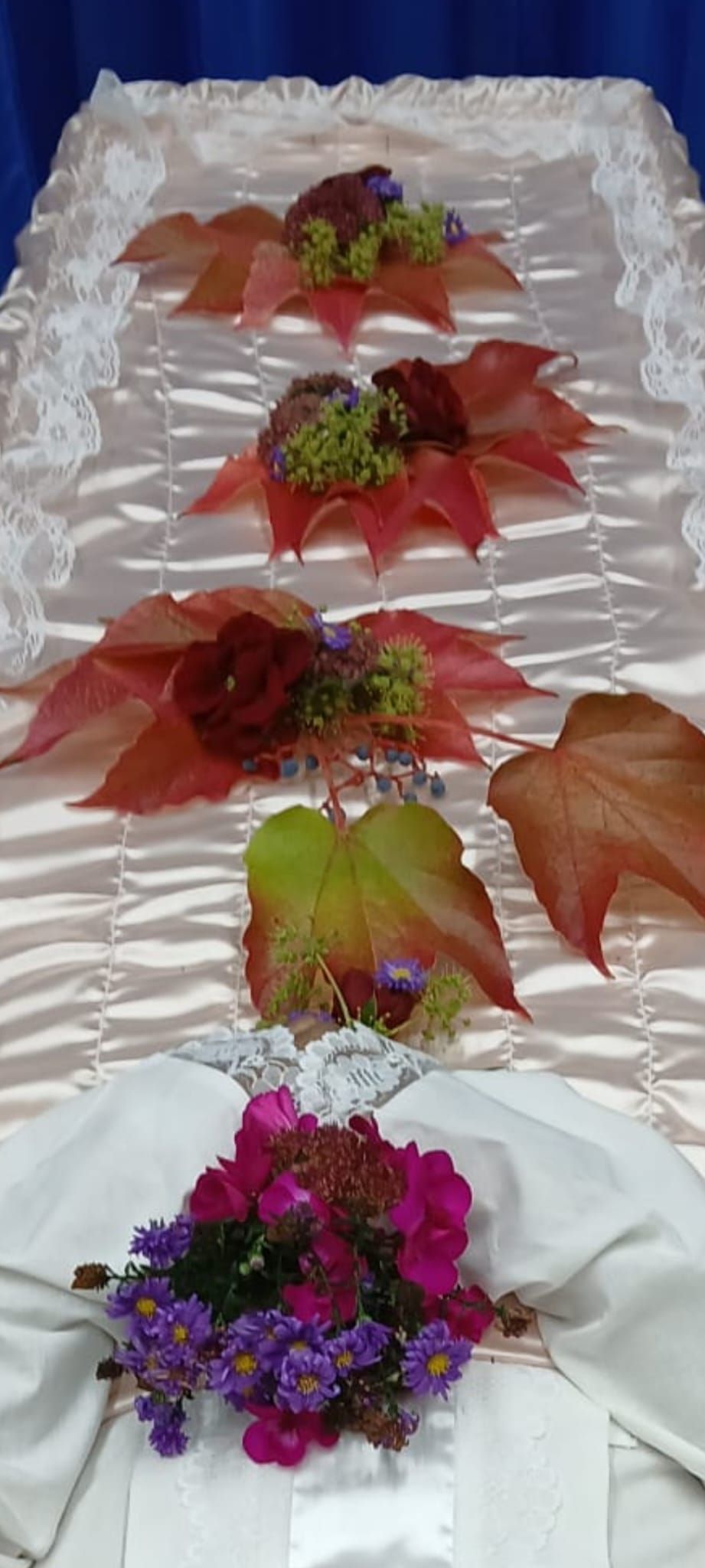 Auf einem Tisch steht ein Sarg mit Blumen und Blättern.