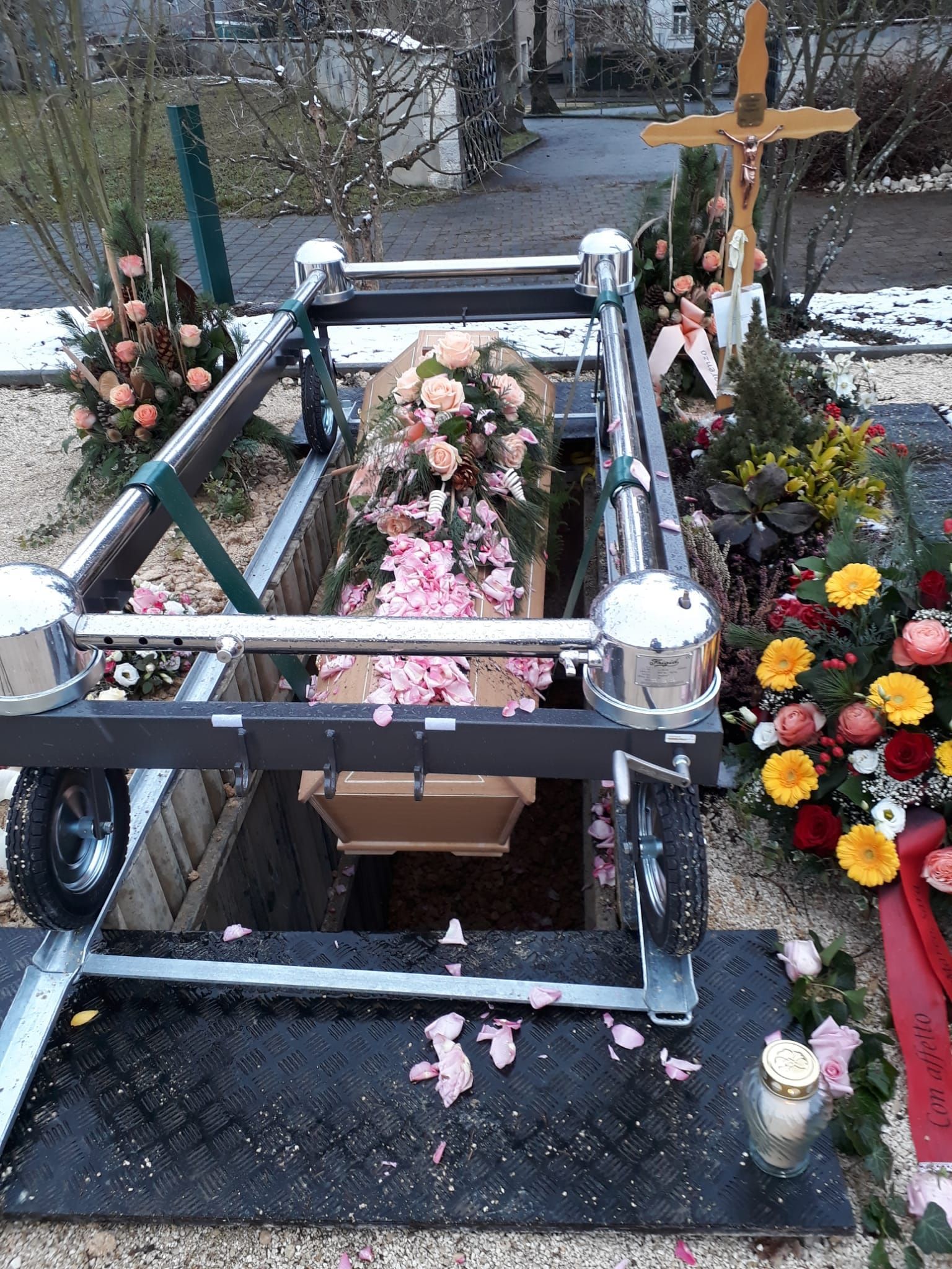 In einem Grab steht ein Sarg mit Blumen und einem Kreuz.