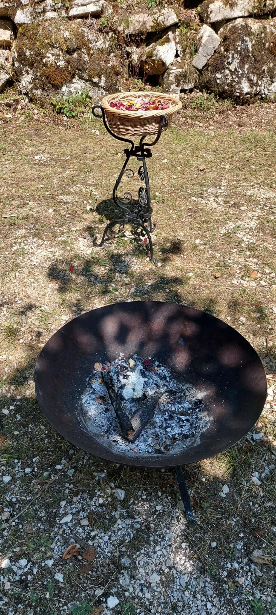 Neben einem Vogelbad steht auf dem Boden eine Feuerstelle.