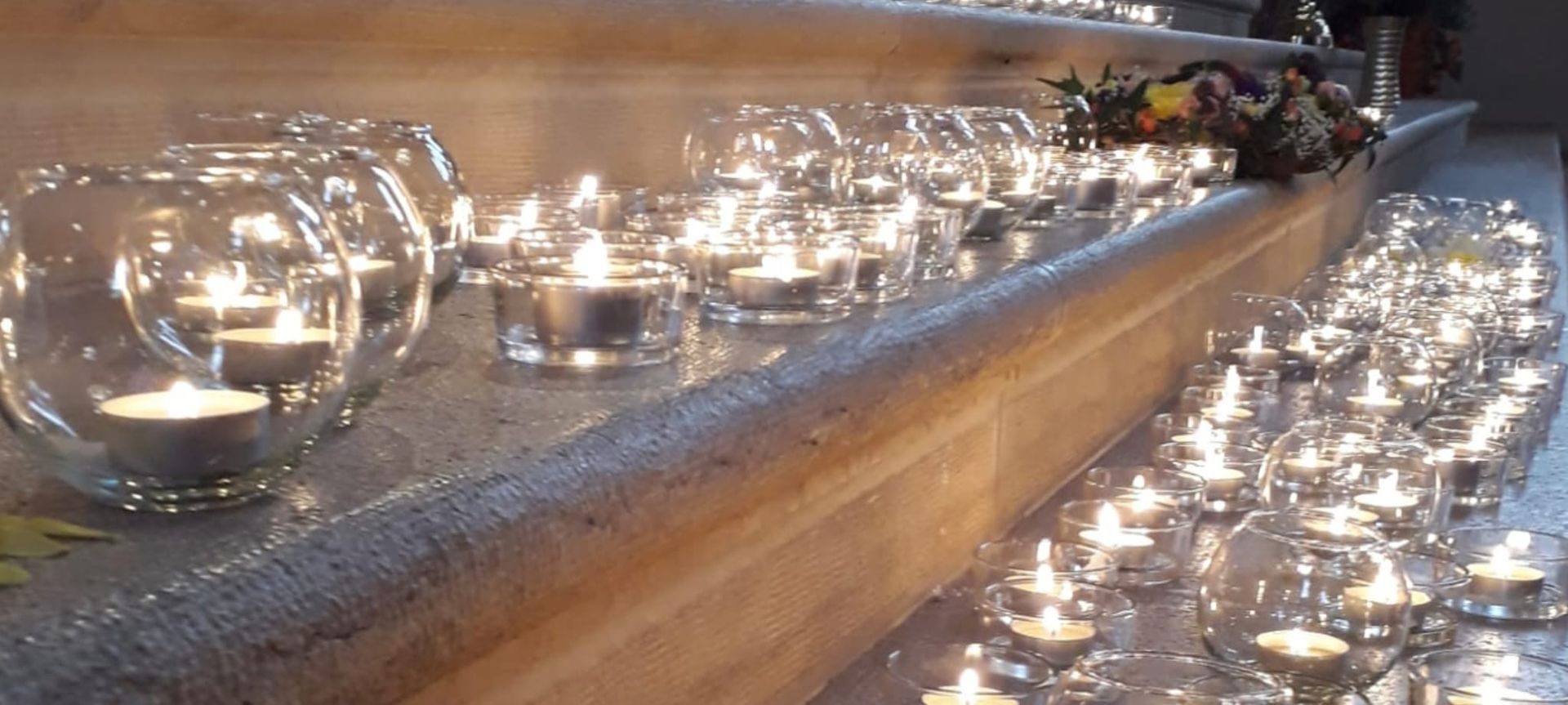 Auf einer Treppe steht eine Reihe Kerzen.