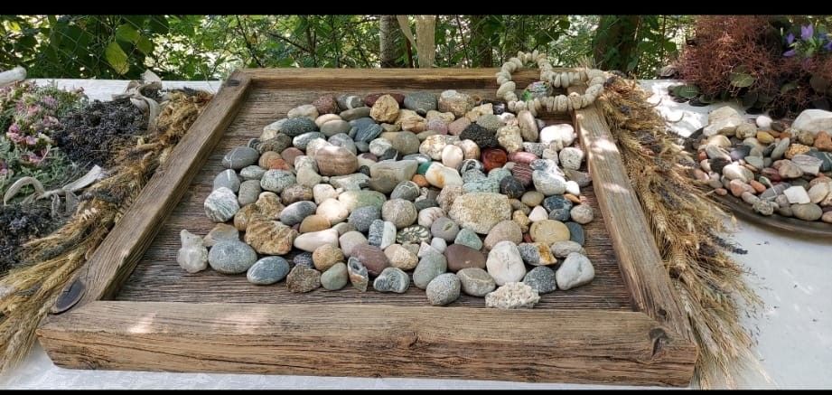 Auf einem Tisch steht ein mit Steinen gefülltes Holztablett.