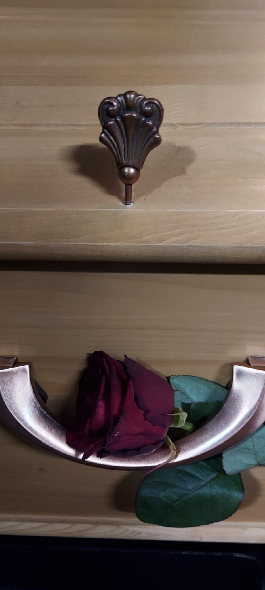 Eine rote Rose liegt auf einer Holzschublade.