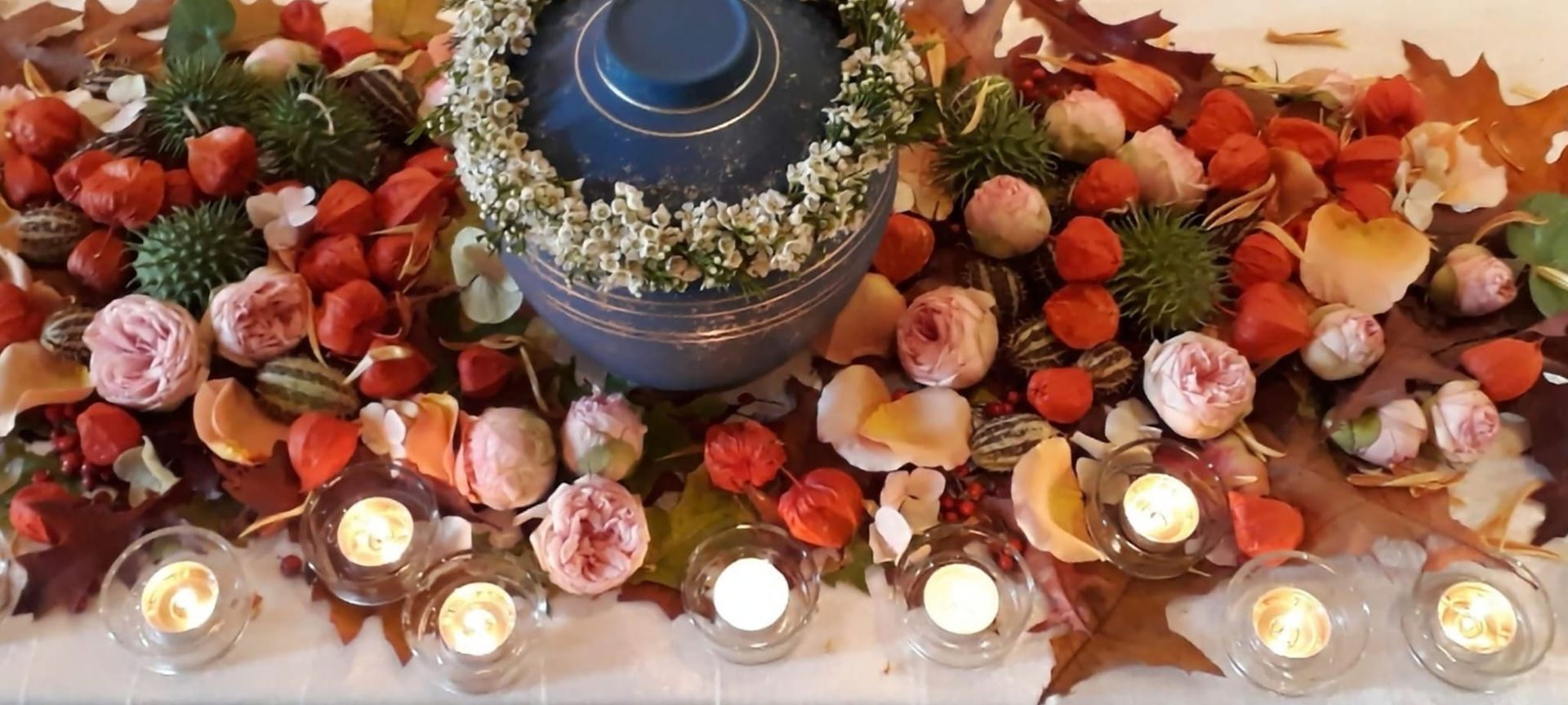 Ein Tisch mit Kerzen, Blumen und Blättern.