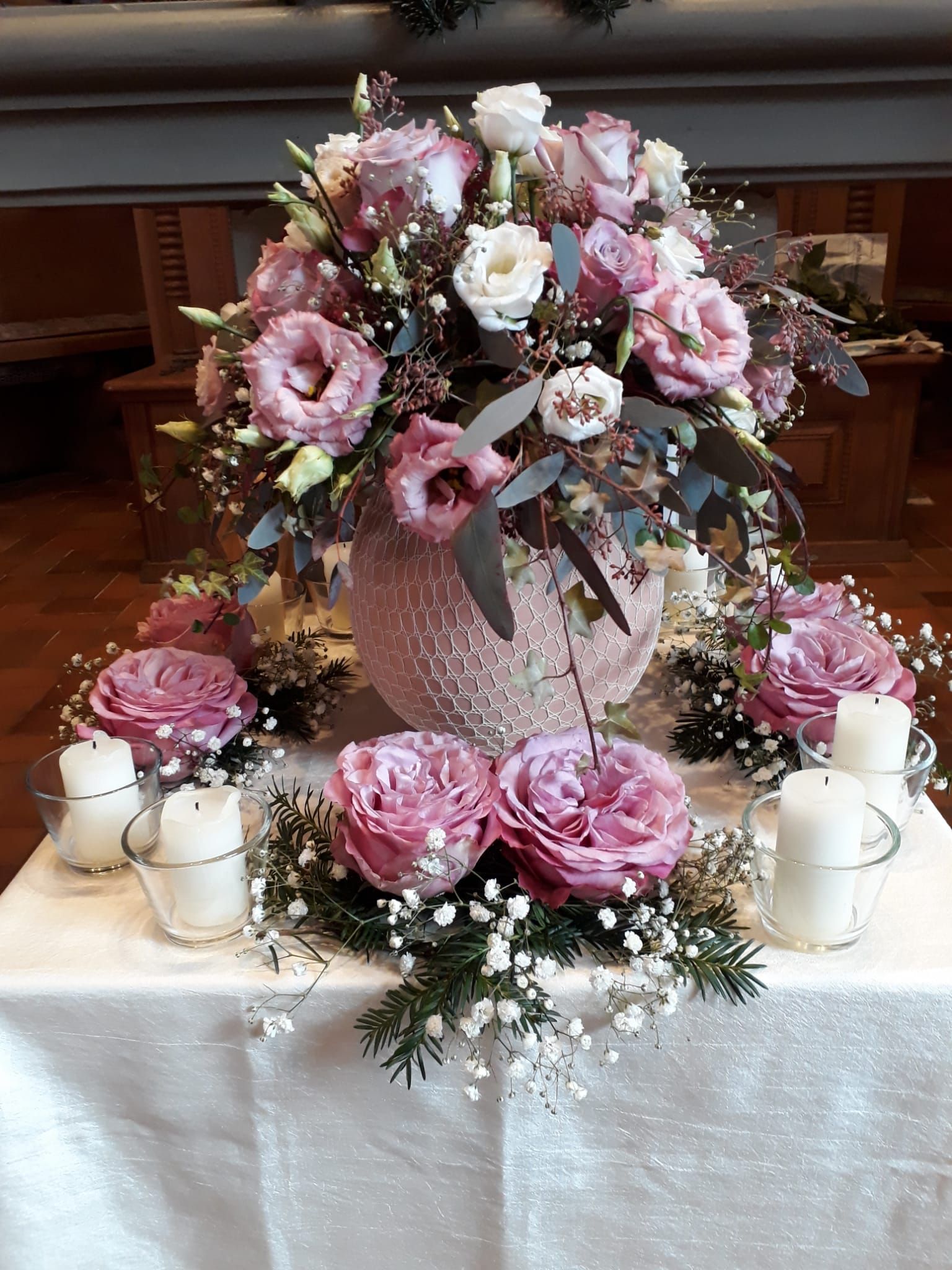 Eine Vase mit rosa Blumen und Kerzen auf einem Tisch.
