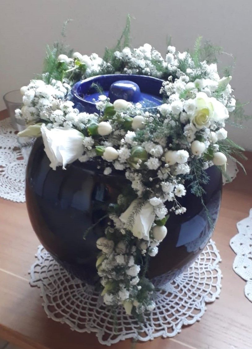 Eine schwarze Vase mit weißen Blumen und Schleierkraut gefüllt