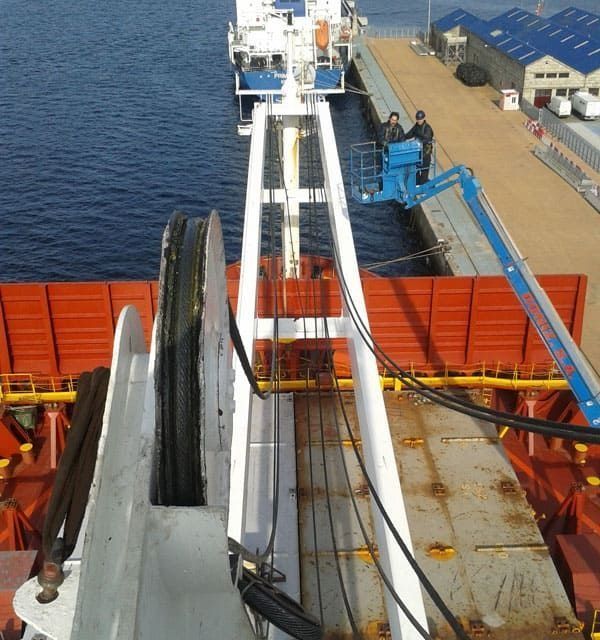 Un gran barco está atracado en un muelle con una grúa adjunta.