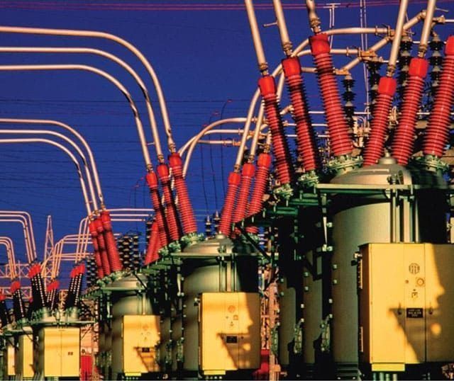 Una fila de transformadores eléctricos con un cielo azul al fondo