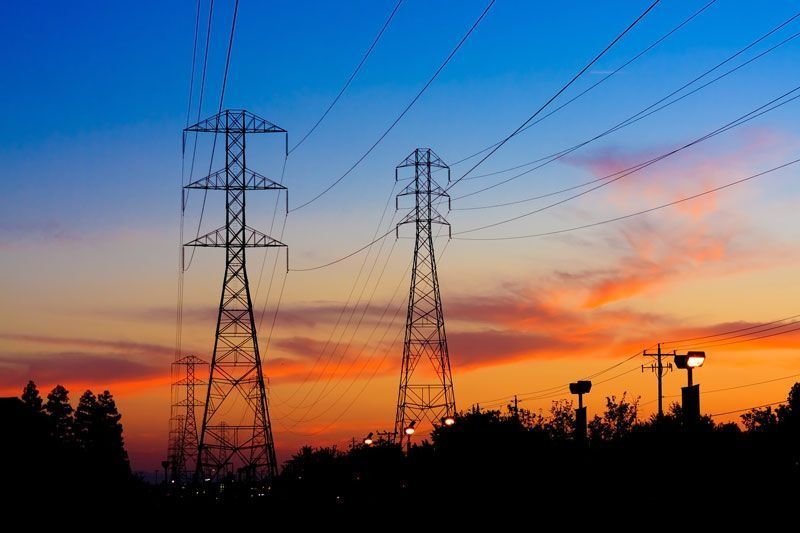 Dos líneas eléctricas se recortan contra el cielo del atardecer.