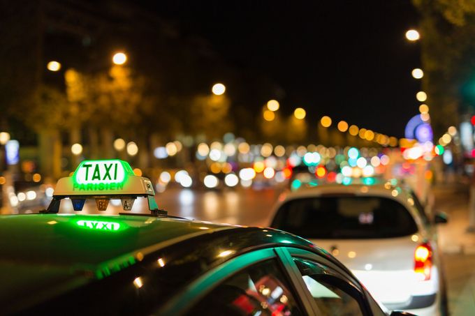 Un taxi vert dans une rue de la ville, la nuit, avec des lampadaires et de la circulation en arrière-plan.