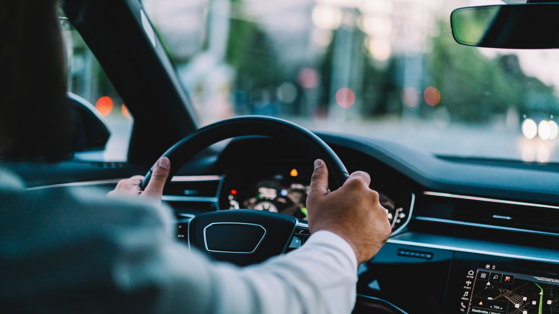 Les mains sur le volant, au volant d'une voiture avec un arrière-plan urbain flou.