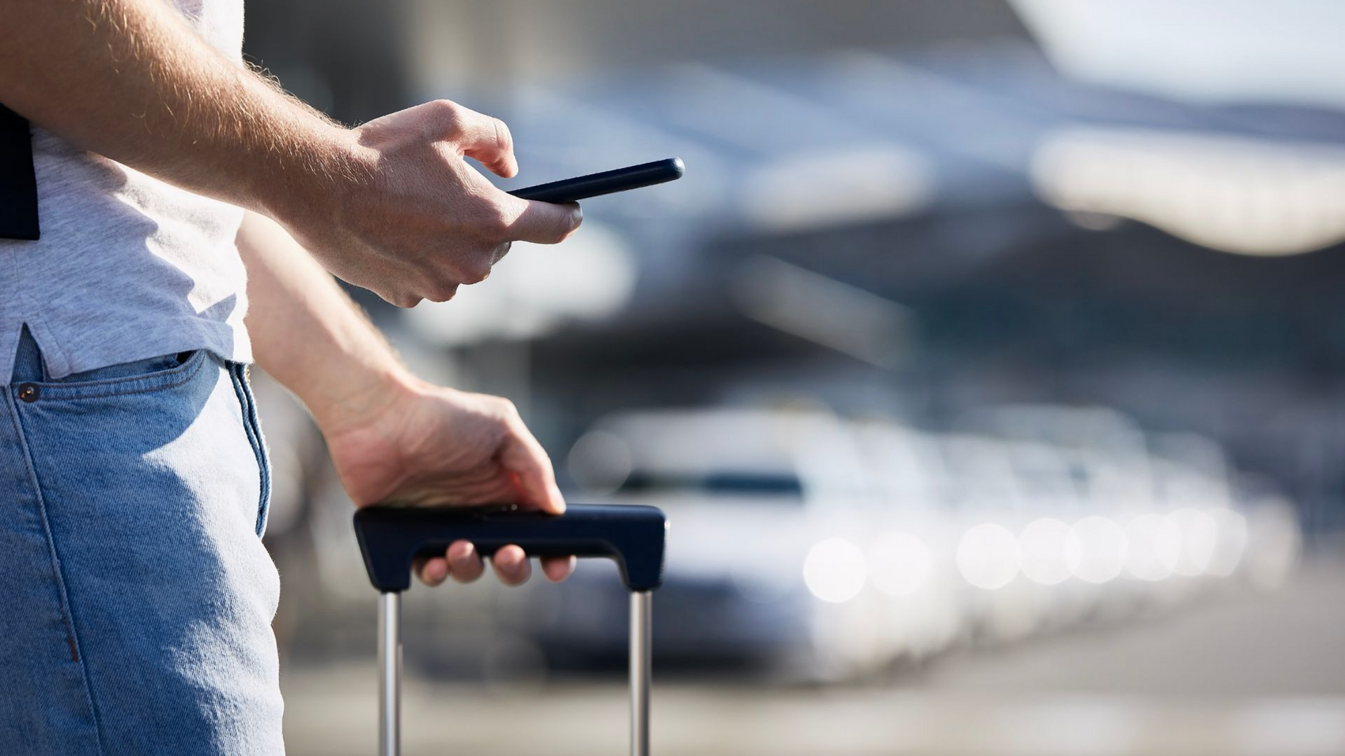 Personne avec des bagages utilisant un téléphone, arrière-plan d'aéroport.