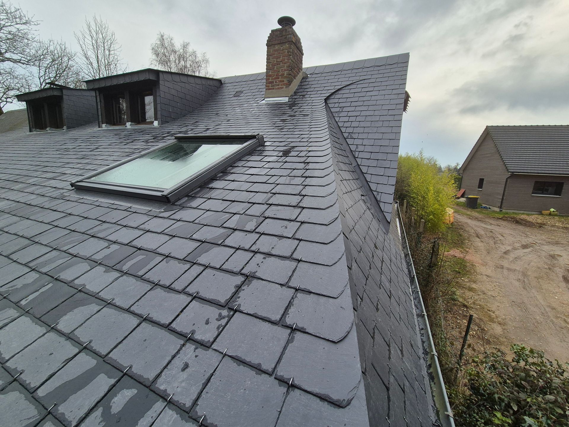 Intervention pour des travaux de fumisterie et de couverture sur une maison avec un toit en ardoises.